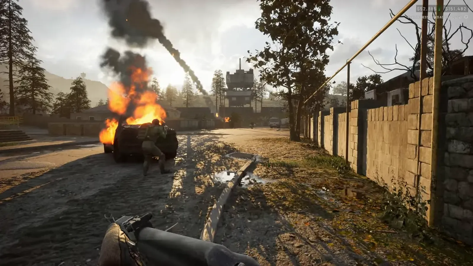 A WARDOGS soldier near a burning vehicle on a village road